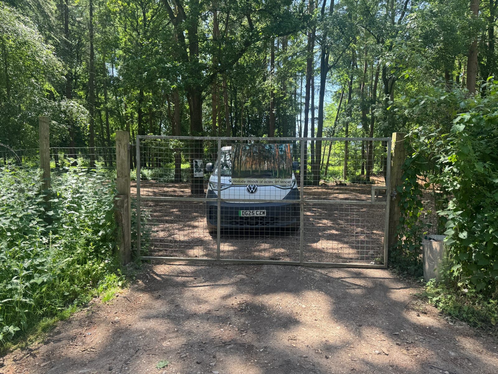Wallaby Woods gate from outside, K9 van parked just inside in dappled pine light